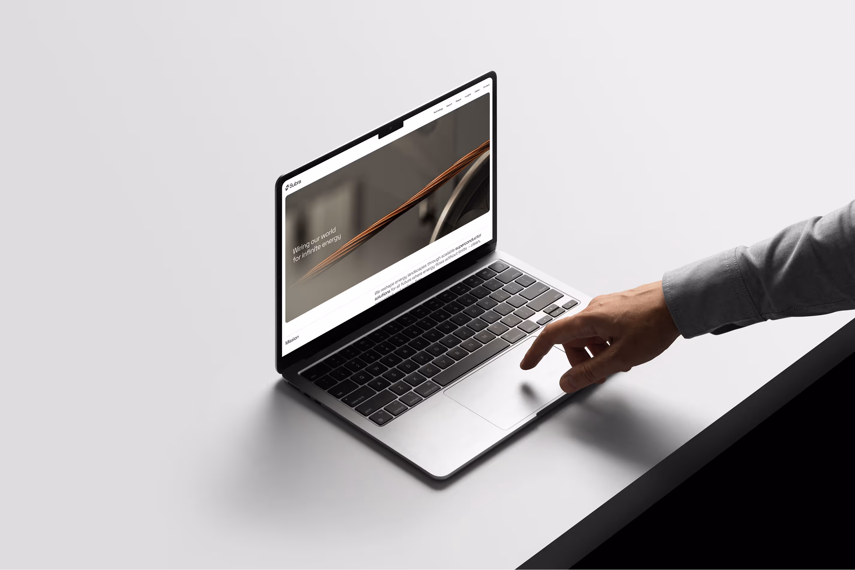 Hand reaching to touch the trackpad of a laptop showing a webpage about wiring for infinite energy.