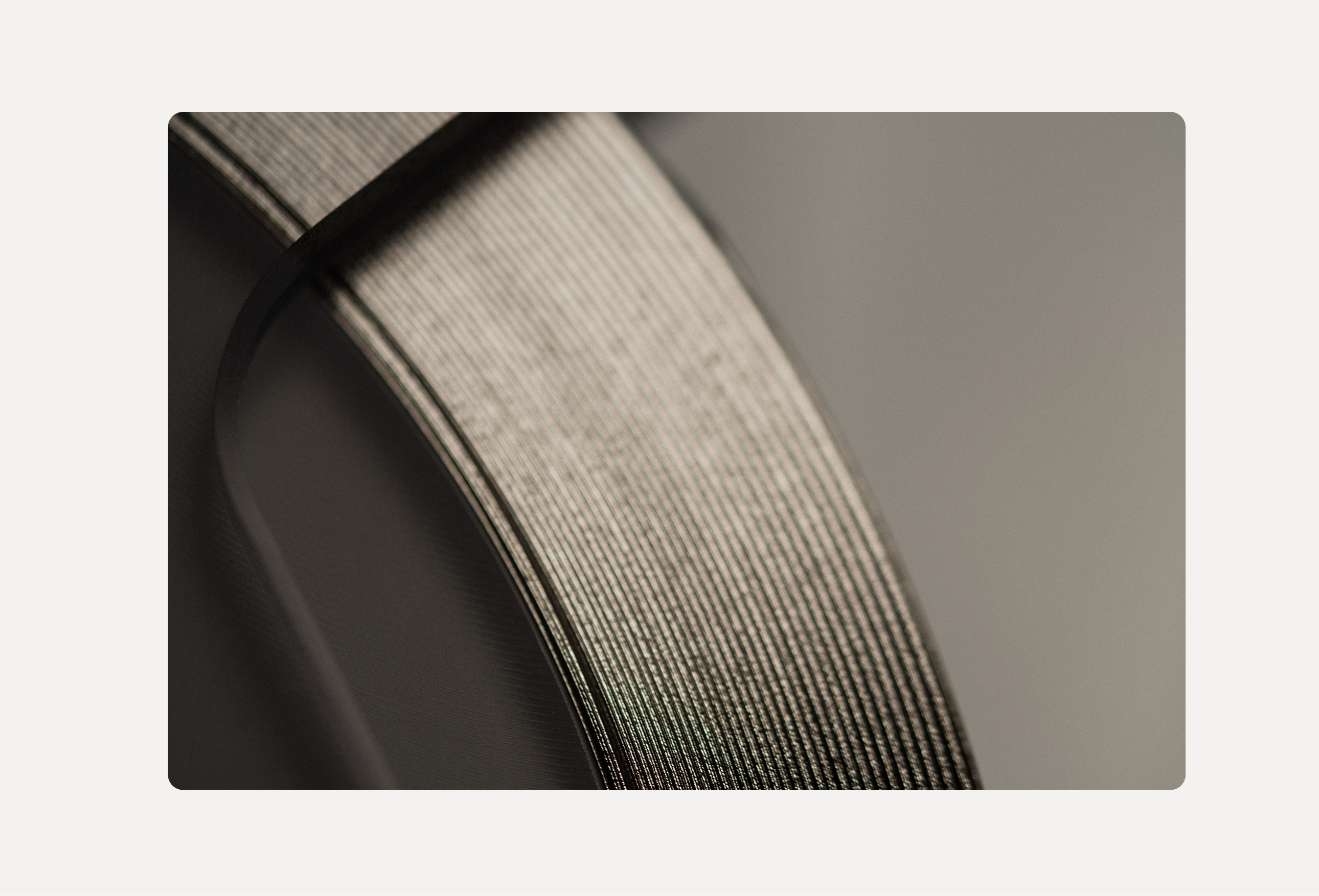 Close-up of two metallic ribbons with textured surfaces overlapping on a soft gray background.