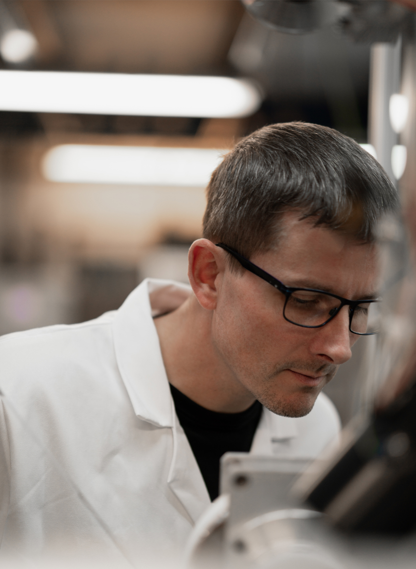 Close-up of a transparent round wheel with metal center and screws mounted on a metal frame in a lab setting.