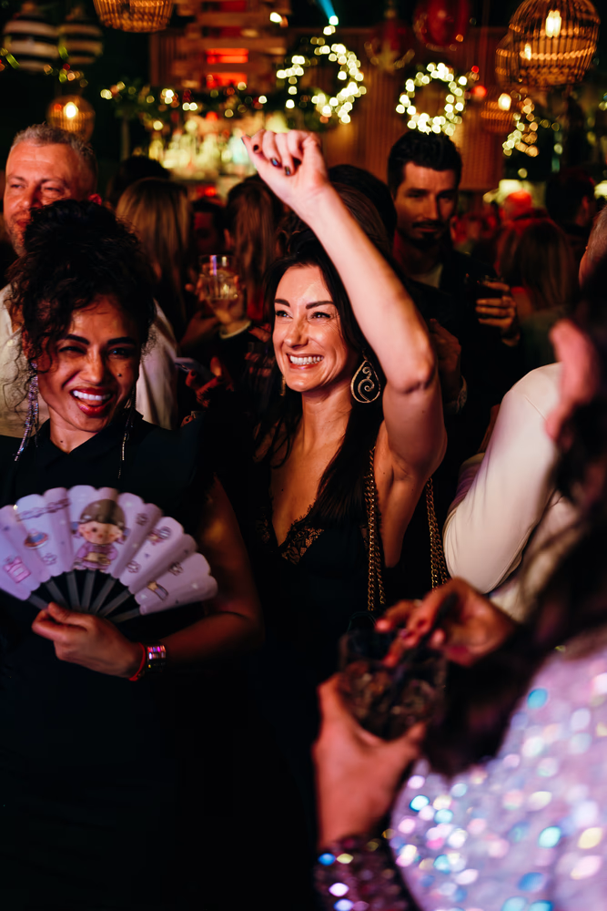 Vrolijke vrouwen die dansen en plezier hebben op een druk feest met sfeerverlichting.