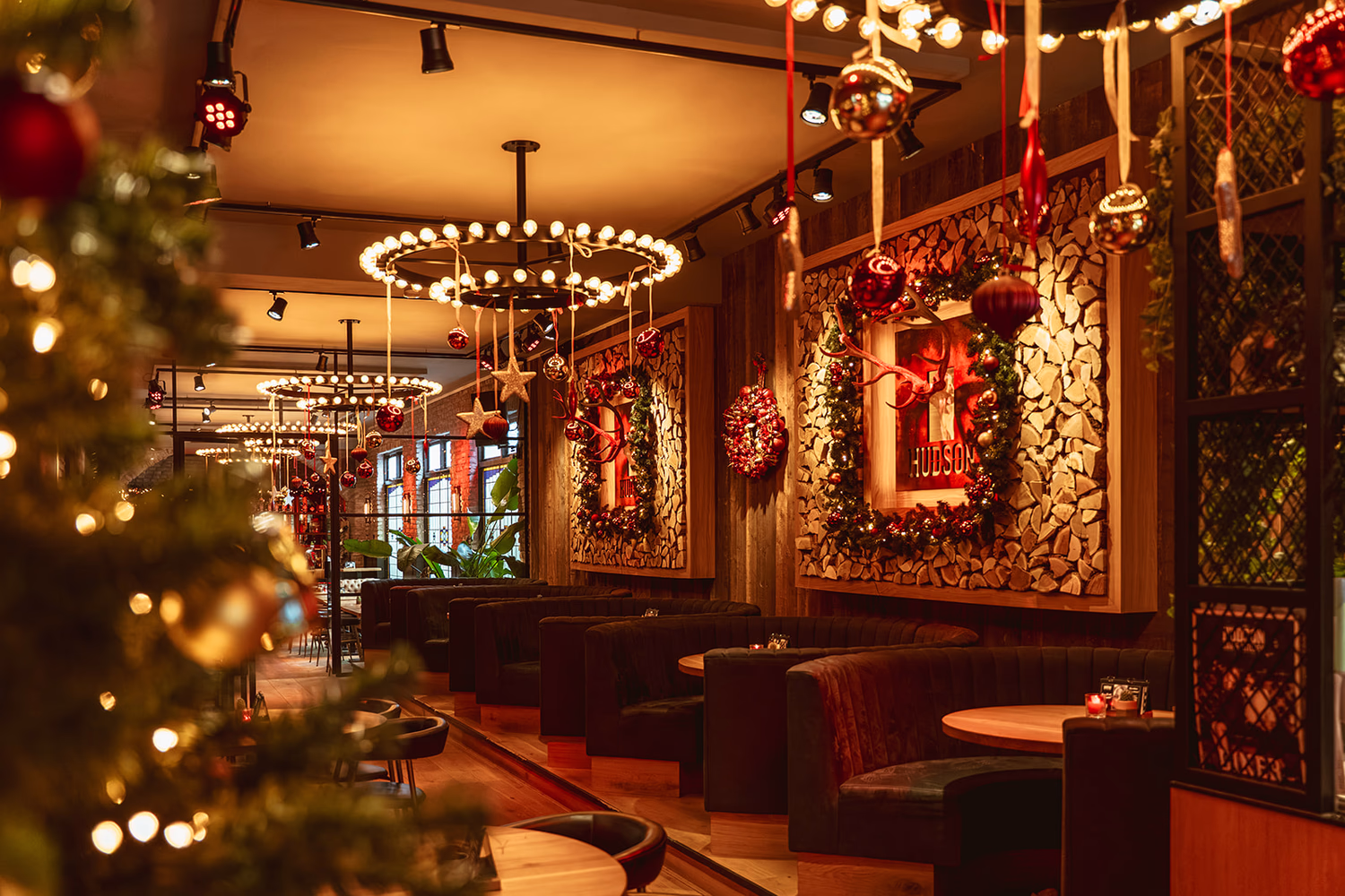 Hamburger op een zwart bord, omgeven door maiskolven met saus, gefrituurde snacks en een glas bier met schuim.