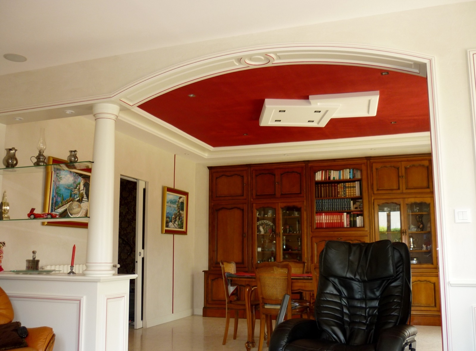 Arche et colonne en staff devant un plafond peint en rouge orné d'un motif blanc