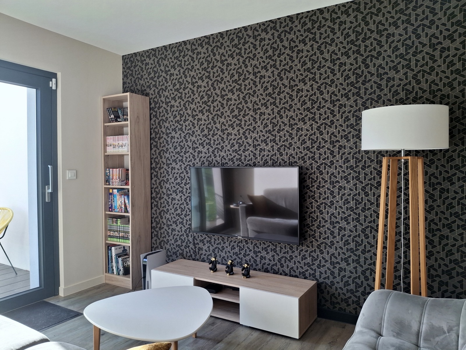 Salon avec mur TV tapissé d'un papier peint à motif graphique sombre