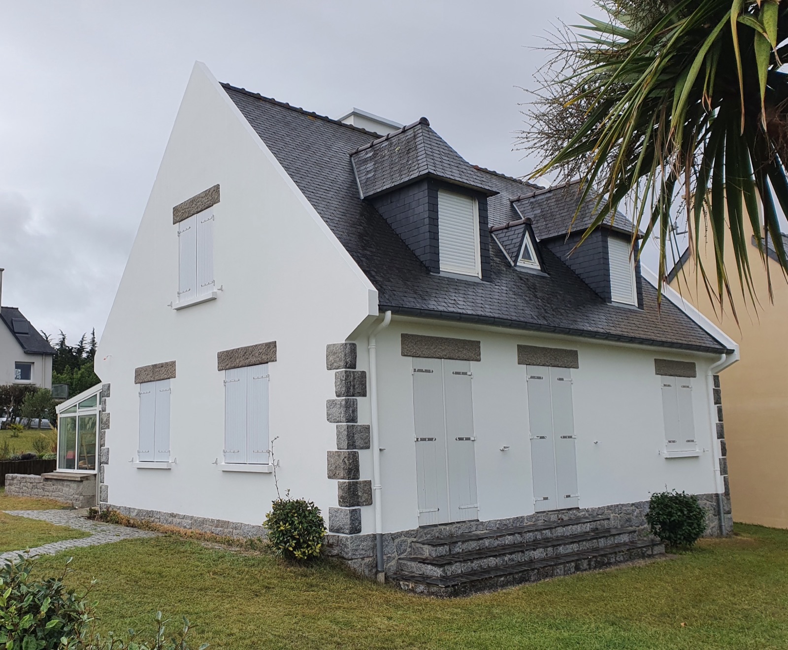Pignon blanc d'une maison néo-bretonne avec chaînes d'angle en granit et toiture en ardoise