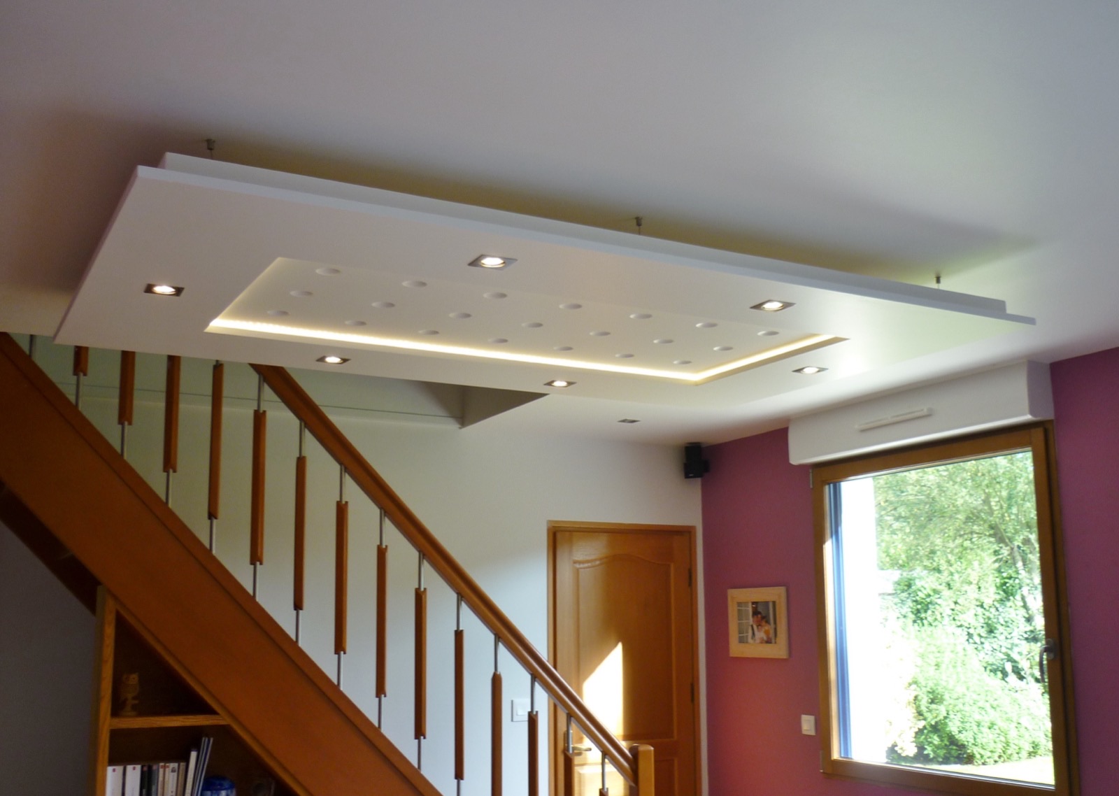 Faux plafond en staff avec spots et éclairage indirect au-dessus d'un escalier en bois