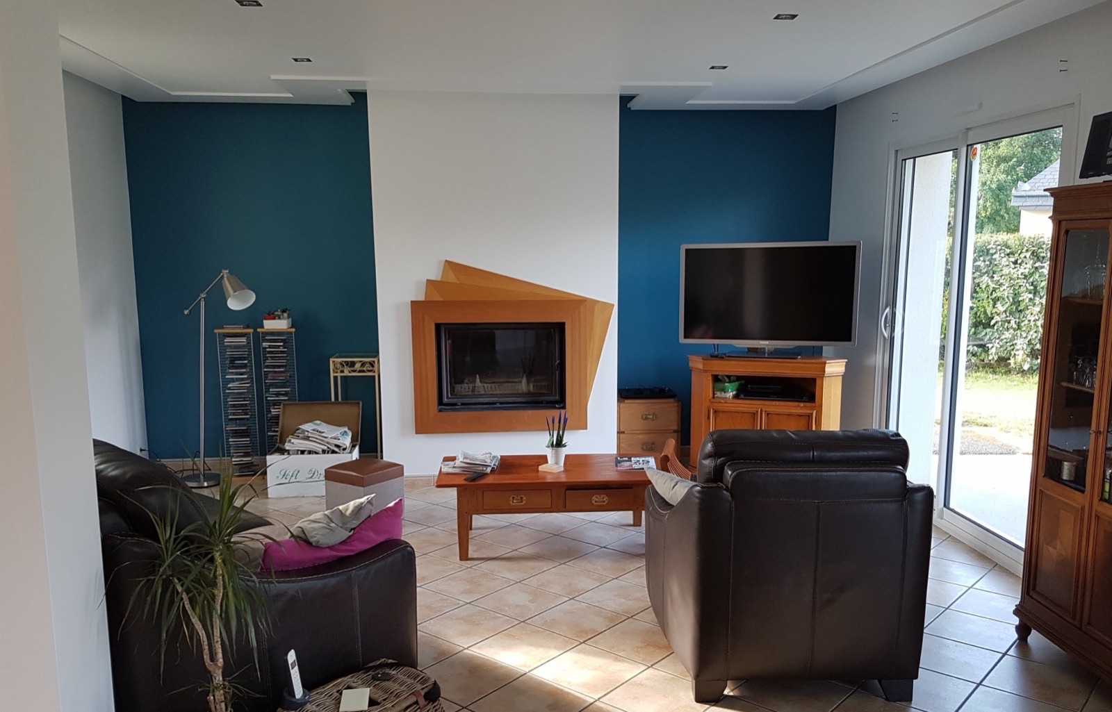 Insert de cheminée entouré d'un habillage en bois, entre deux murs peints bleu canard