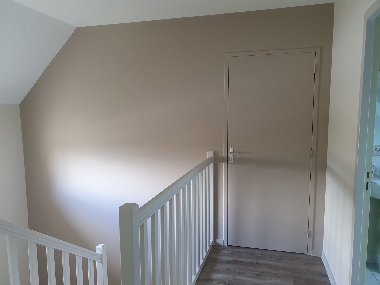Palier d'étage peint en taupe avec porte assortie et rambarde d'escalier blanche