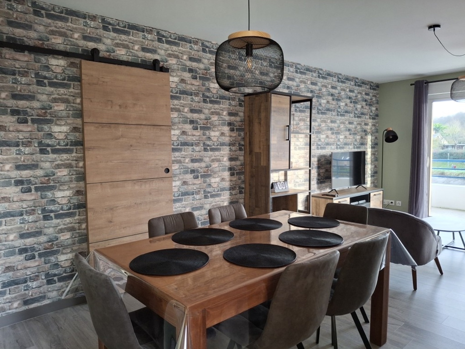 Salle à manger avec mur effet brique, porte coulissante en bois et table