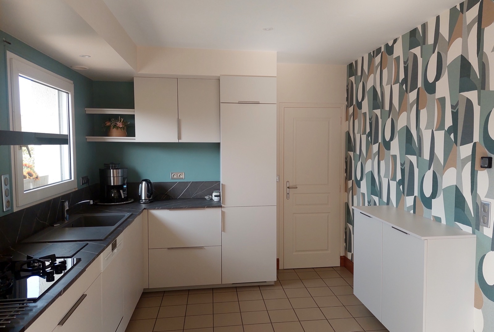 Cuisine avec papier peint à motif géométrique sur un mur et mur peint bleu-vert