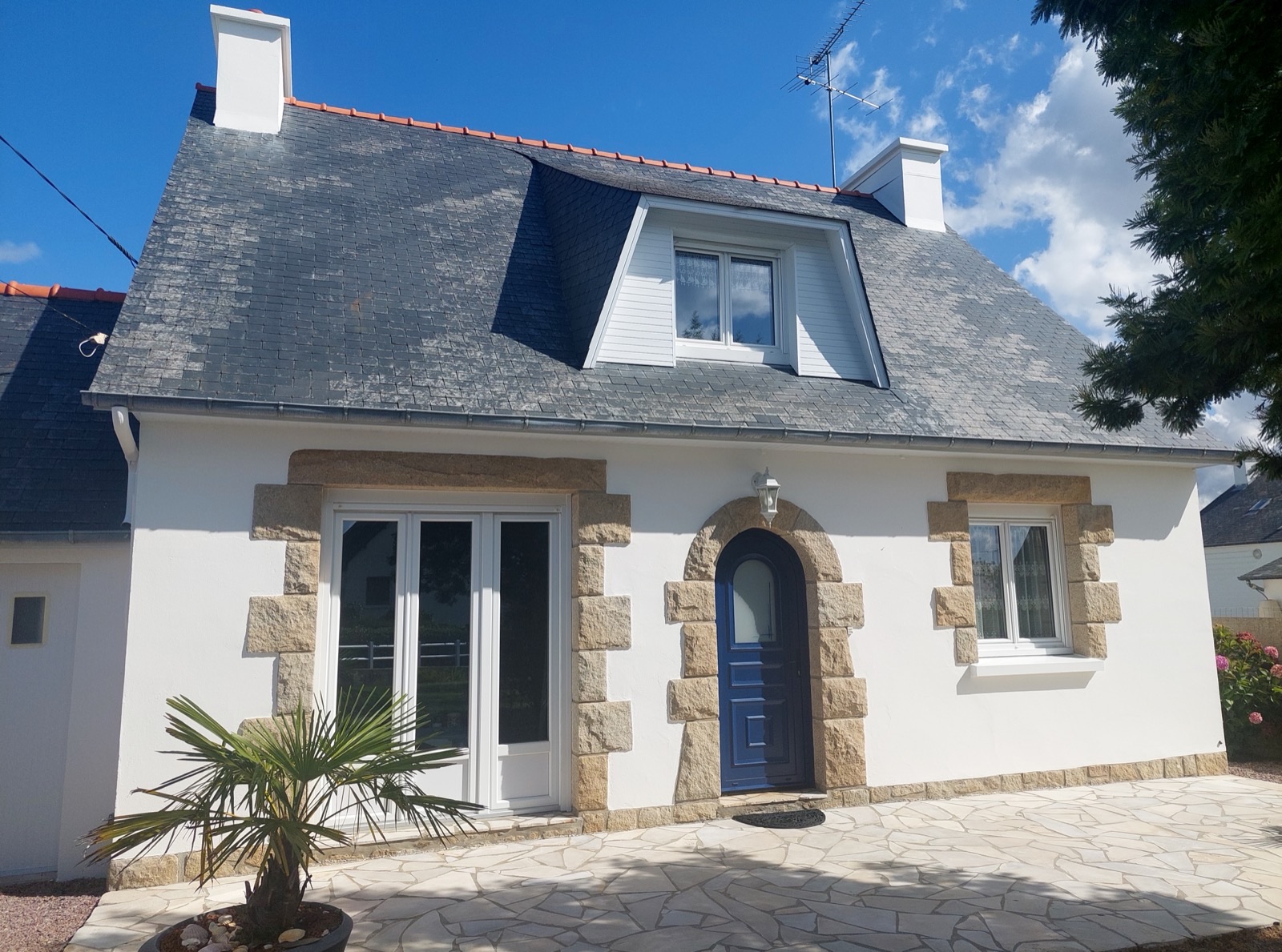 Maison bretonne blanche avec encadrements de fenêtres en granit, lucarne et porte d'entrée bleue