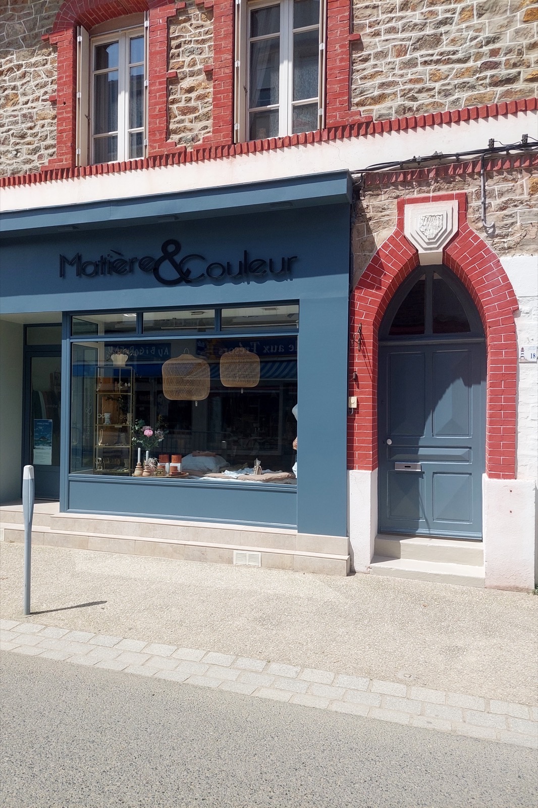 Devanture de commerce peinte en bleu dans une façade en pierre et brique rouge