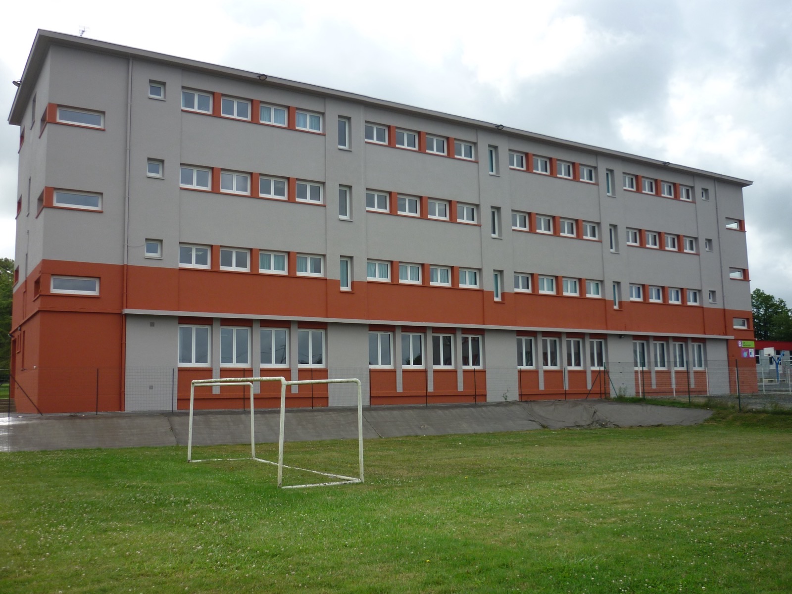 Bâtiment collectif de plusieurs étages à façade grise rythmée de bandeaux orange