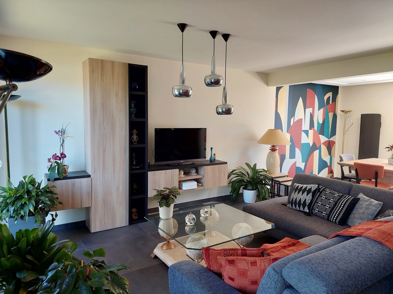 Salon avec fresque géométrique colorée peinte sur un pan de mur près du coin repas