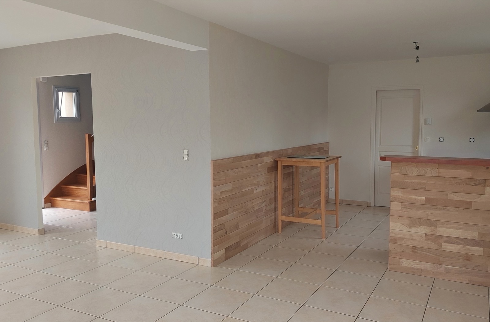 Séjour aux murs gris avec habillage en lames de bois à mi-hauteur et carrelage clair