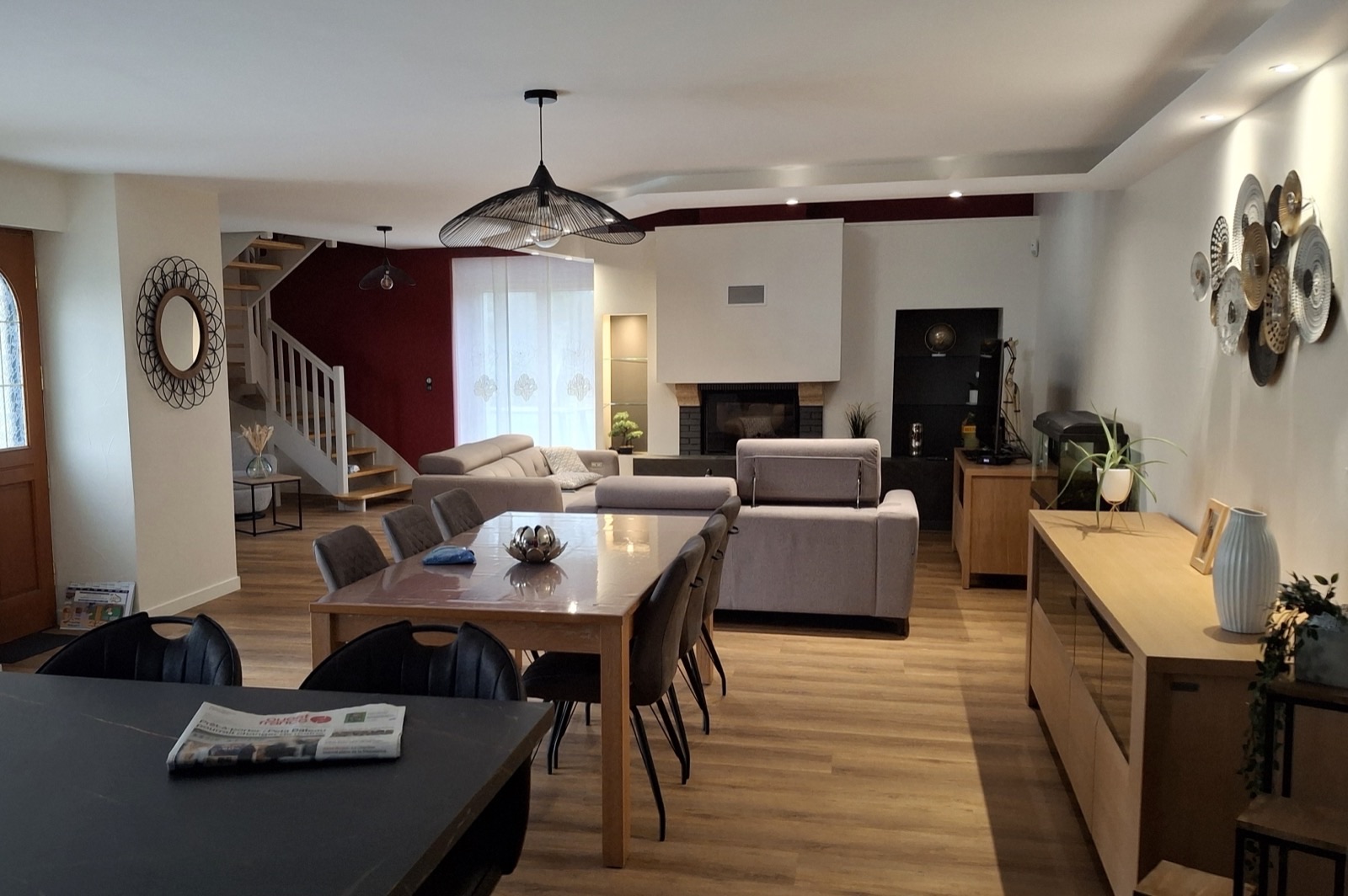 Séjour rénové avec mur rouge près de l'escalier, parquet clair et coin salon