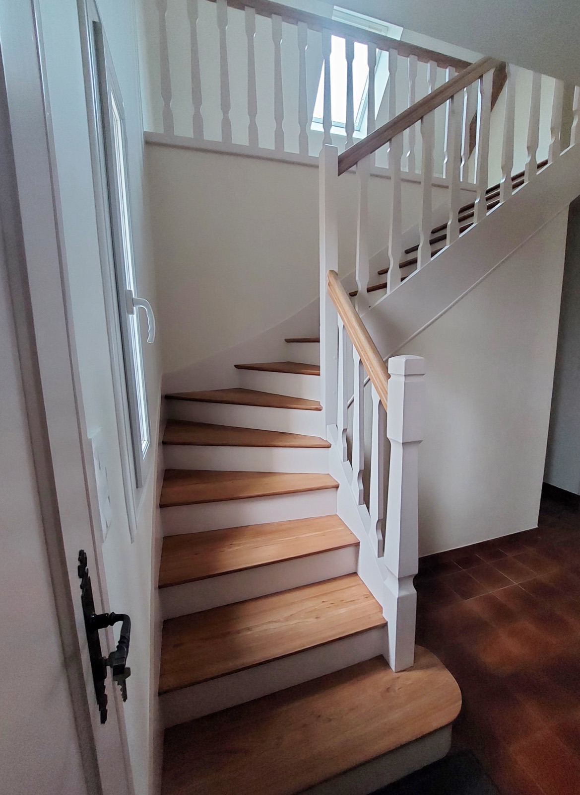 Escalier peint en blanc avec marches en bois vernies et rampe à balustres blancs