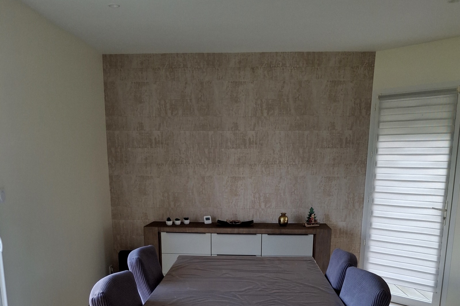 Salle à manger avec un mur beige à effet matière derrière un buffet