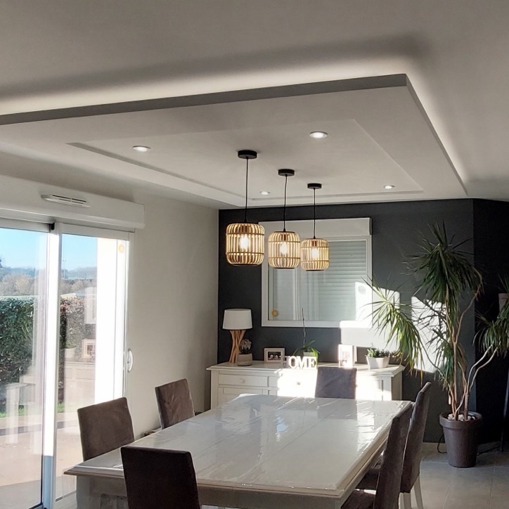 Caisson de plafond en staff avec spots au-dessus d'une table de salle à manger et suspensions
