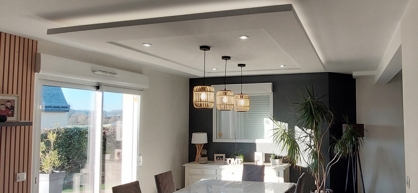 Caisson de plafond en staff avec spots au-dessus d'une table de salle à manger et suspensions