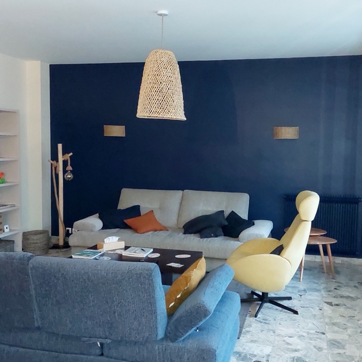 Salon avec un mur d'accent bleu nuit, bibliothèque blanche et fauteuil jaune