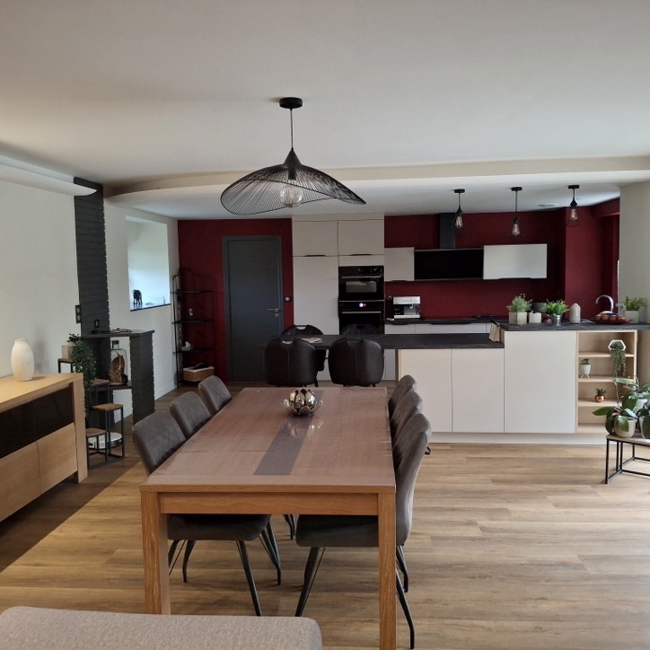 Cuisine ouverte avec mur bordeaux, parquet clair et grande table de salle à manger
