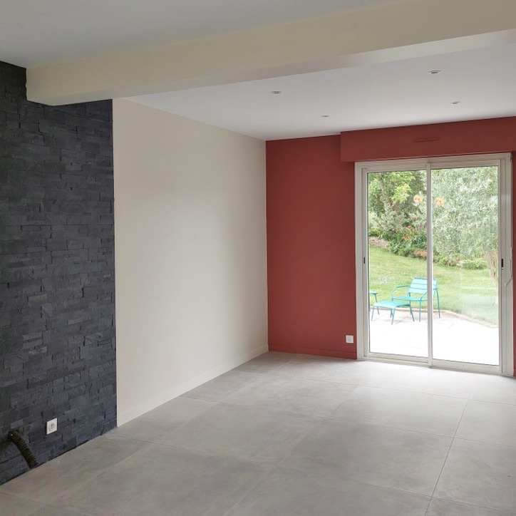 Séjour avec mur en plaquettes de parement aspect ardoise noire et mur peint rouge