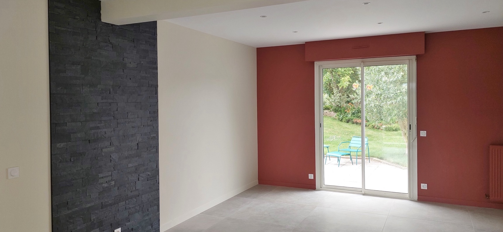 Séjour avec mur en plaquettes de parement aspect ardoise noire et mur peint rouge