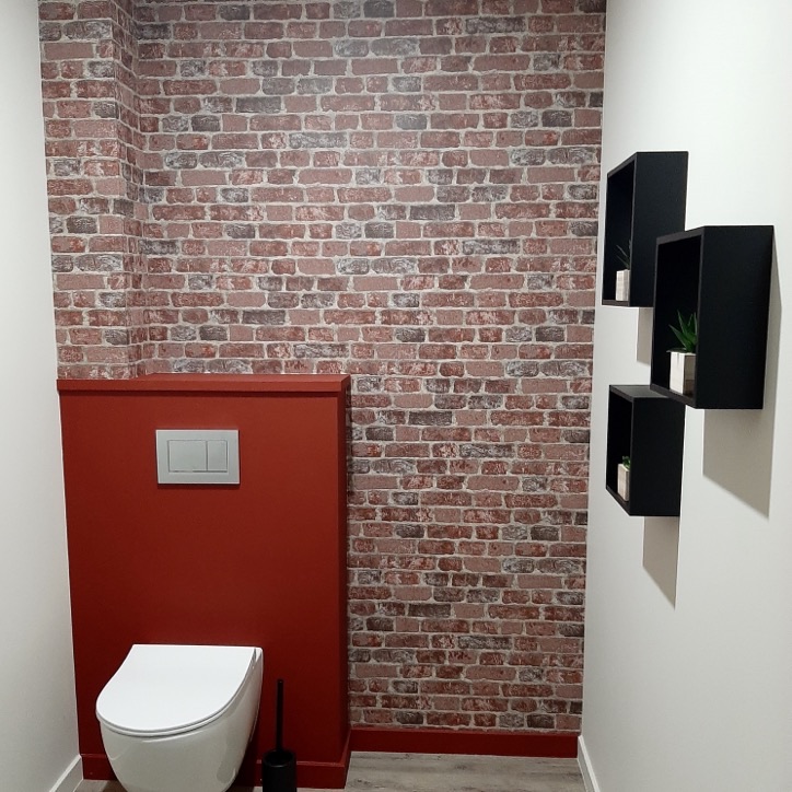 WC suspendu avec papier peint effet brique et coffrage peint en rouge