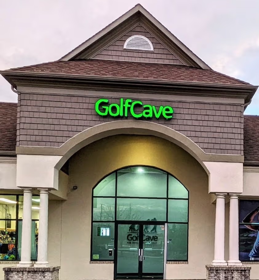 Two men standing in the parking lot looking up at a GolfCave sign on a building