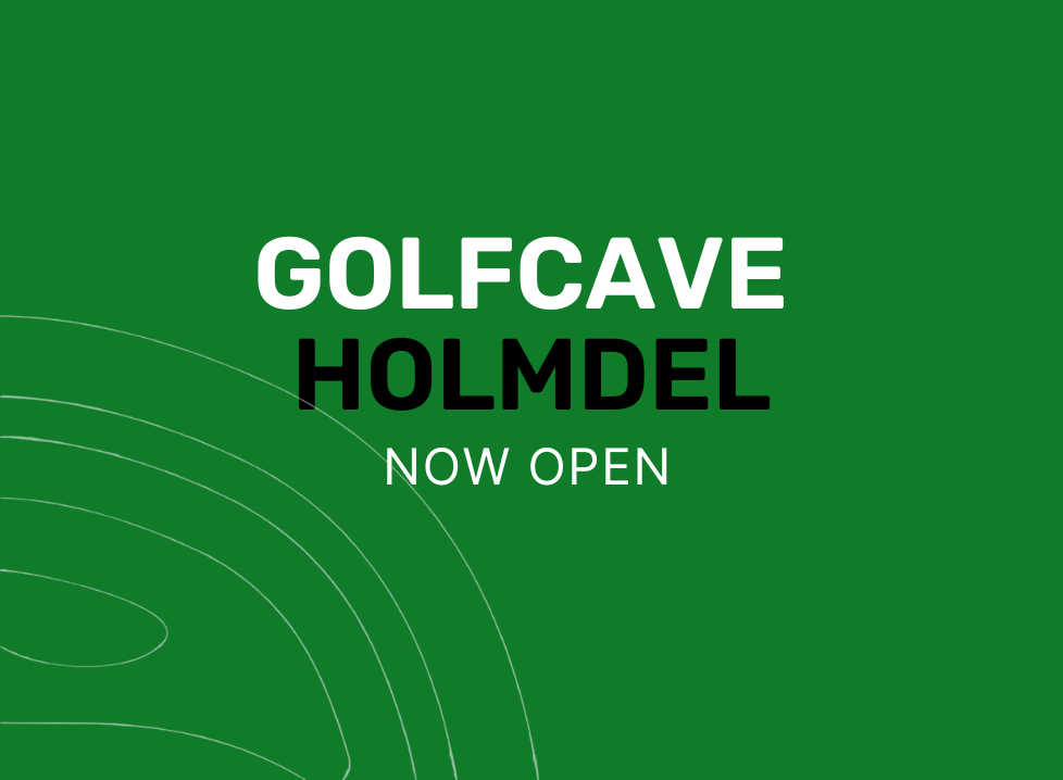 Two men playing golf at the GolfCave. One man is over the ball about to hit while the other watches