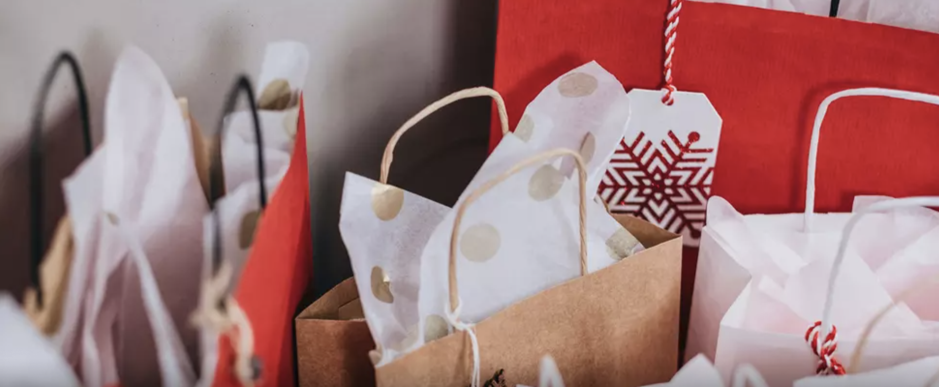 A bunch of holiday gift bags with tissue paper sticking out
