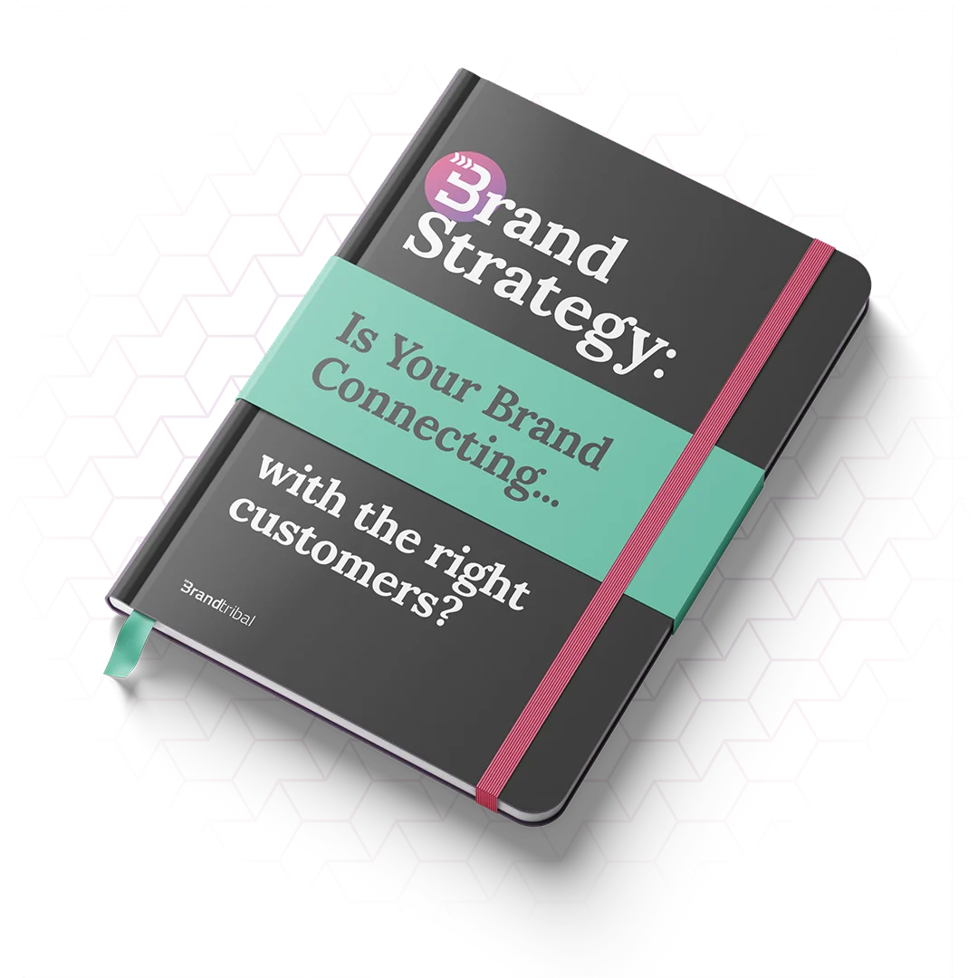 Closed black notebook with pink elastic band and turquoise strap reading 'Brand Strategy: Is Your Brand Connecting... with the right customers?'