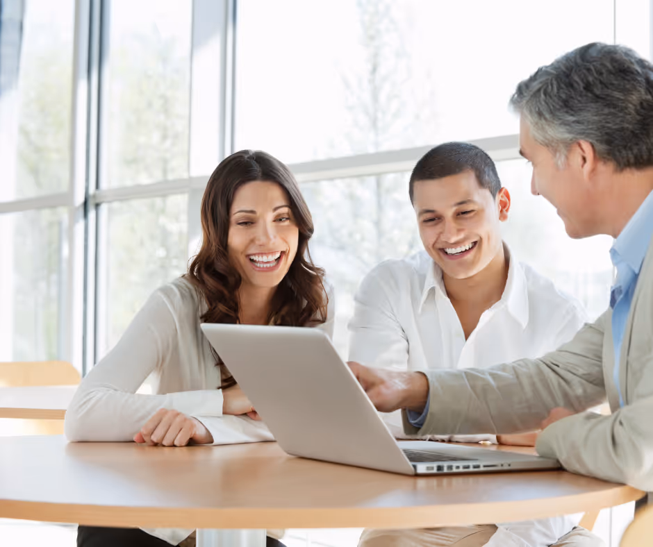Smiling couple with a financial manager looking at a laptop after finding services through SEO for Financial Services.