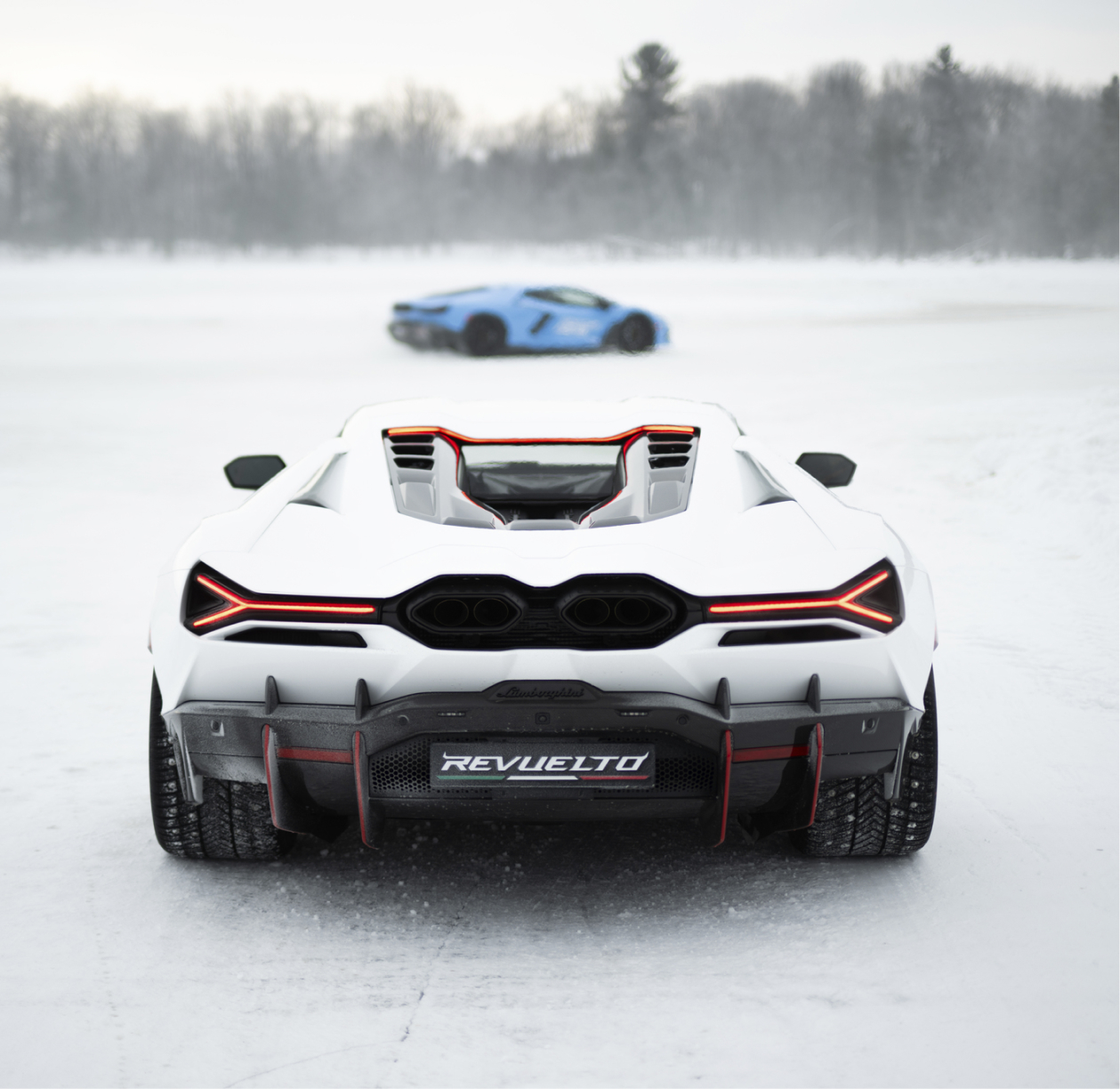 Rear view of Lamborghini Revuelto on ice with another vehicle in motion behind, emphasizing design and cold-weather capability