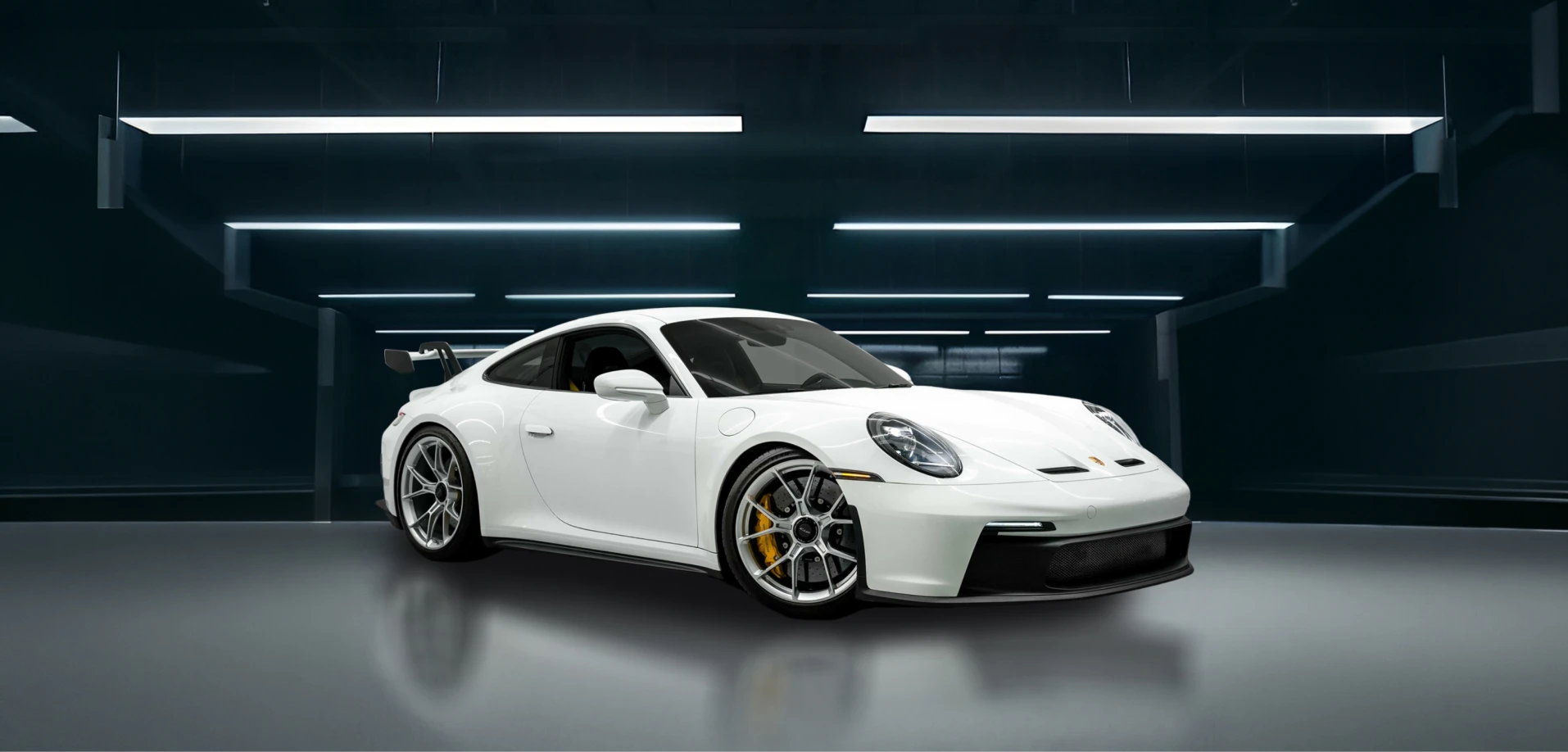 White Porsche 911 in a modern studio with geometric lighting, highlighting precision design and performance-focused aesthetics