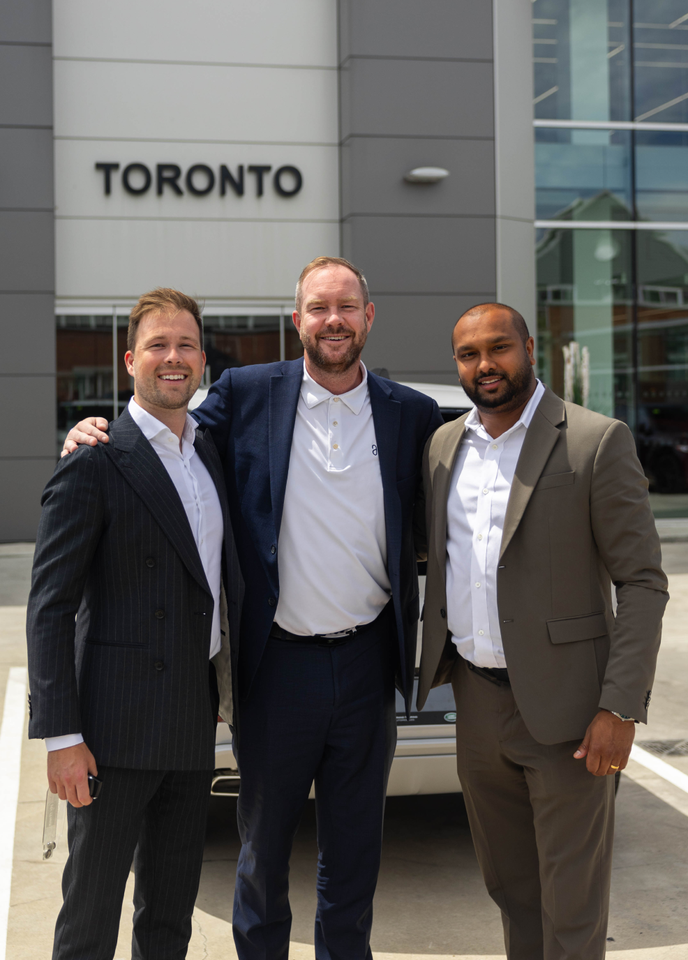 Three JLR Toronto executives standing outside dealership smiling, representing leadership behind successful full‑funnel marketing system.