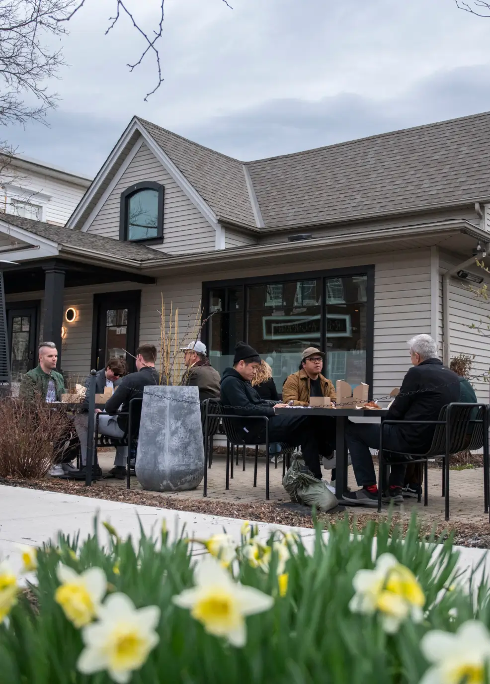 Journalists dining outdoors at a café near Niagara, surrounded by spring flowers, representing the refined hospitality and relaxed atmosphere of the event.
