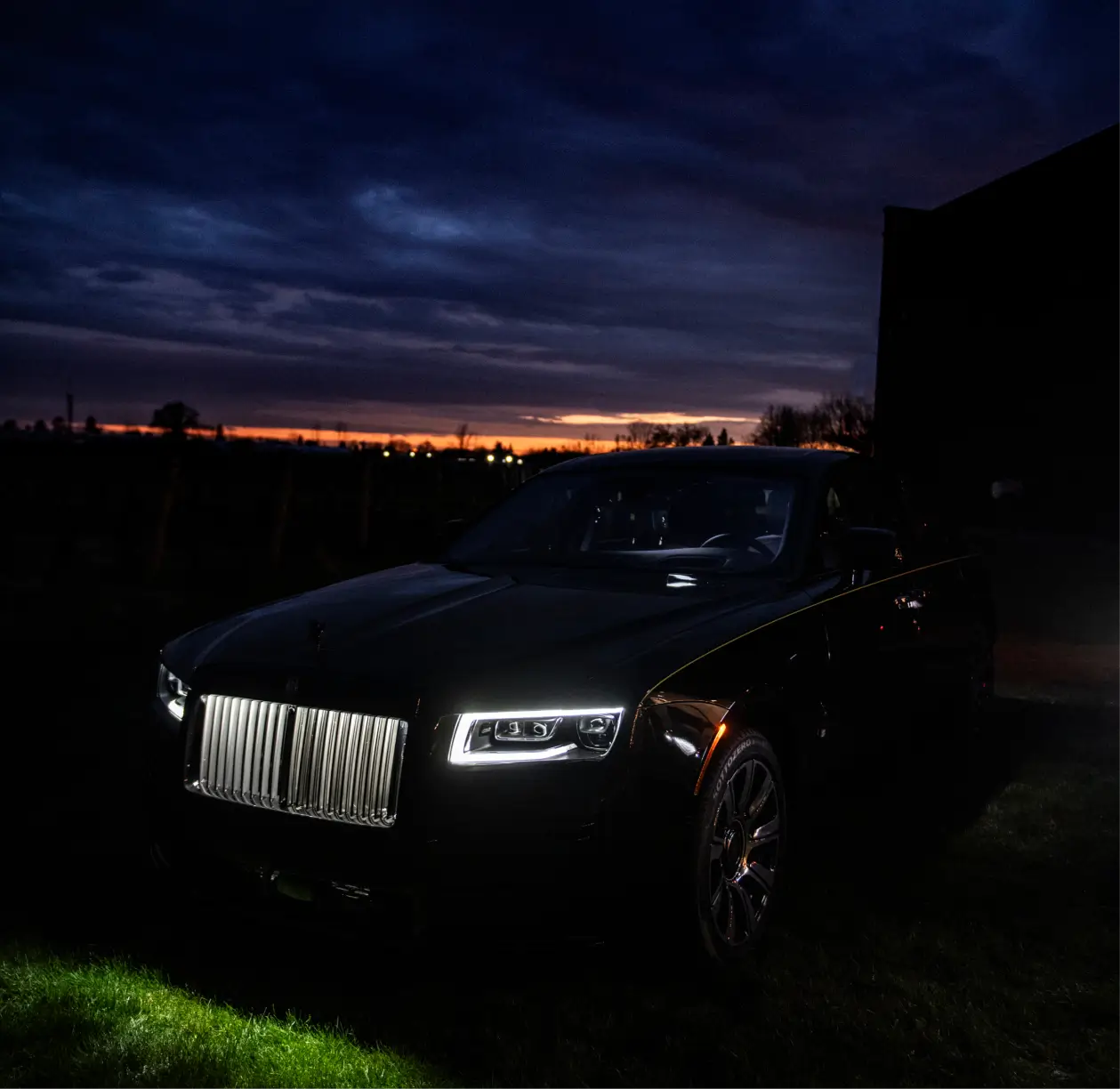 Rolls‑Royce illuminated by headlights at dusk under a deep blue and orange sky, symbolizing elegance and the celestial theme of the campaign’s finale.