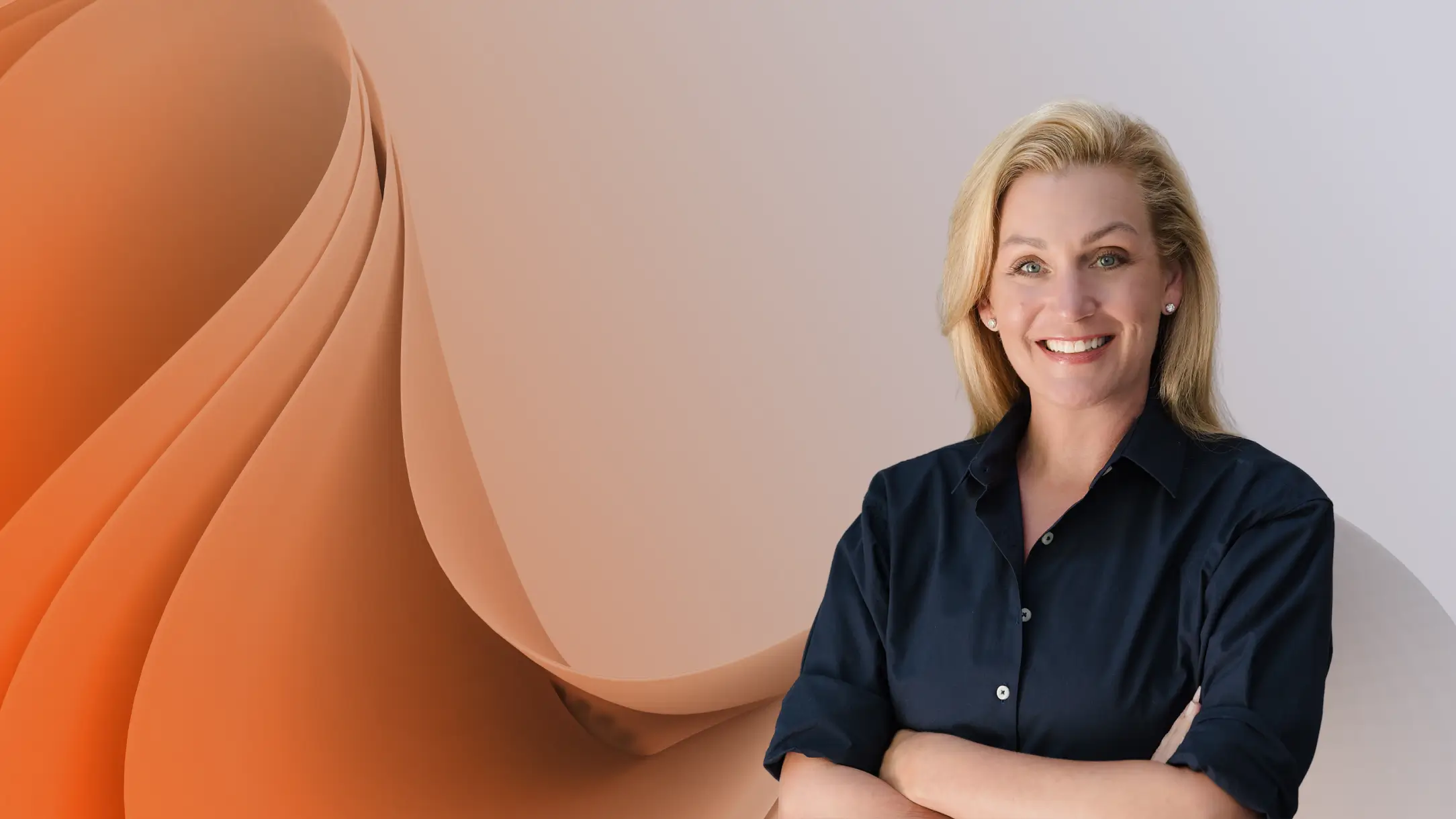Deborah Belcourt smiling in a dark shirt with folded arms against a peach and white abstract background, conveying confidence and professional warmth.