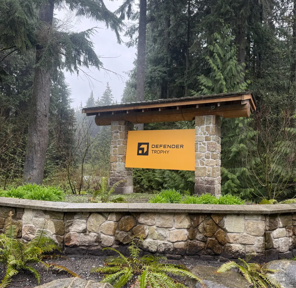Defender Trophy event signage set within a forested venue, establishing the rugged outdoor setting for the North American selection event.
