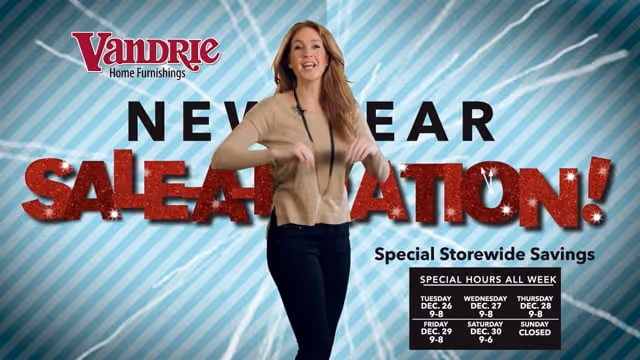 Smiling woman in beige sweater standing in front of a Vandrie Home Furnishings New Year Sale-A-Bration advertisement with storewide savings and special hours.