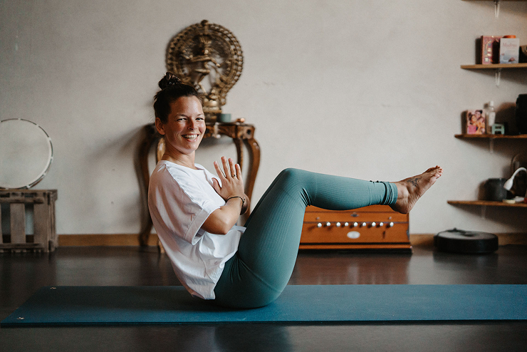 Smiling young woman with long red hair holding multiple paintbrushes in her hand.