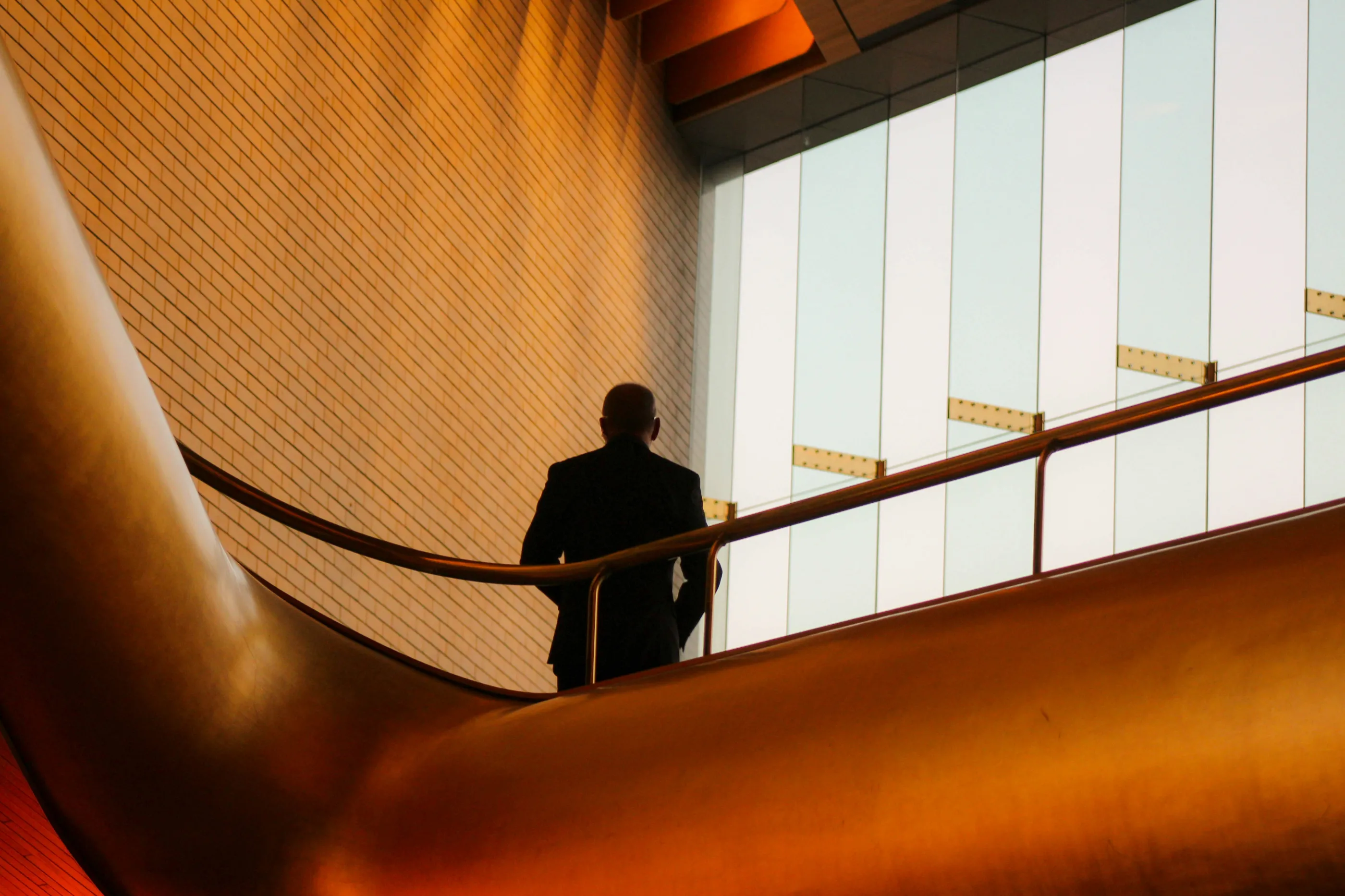 A man in a suit walking up a metal handrail.