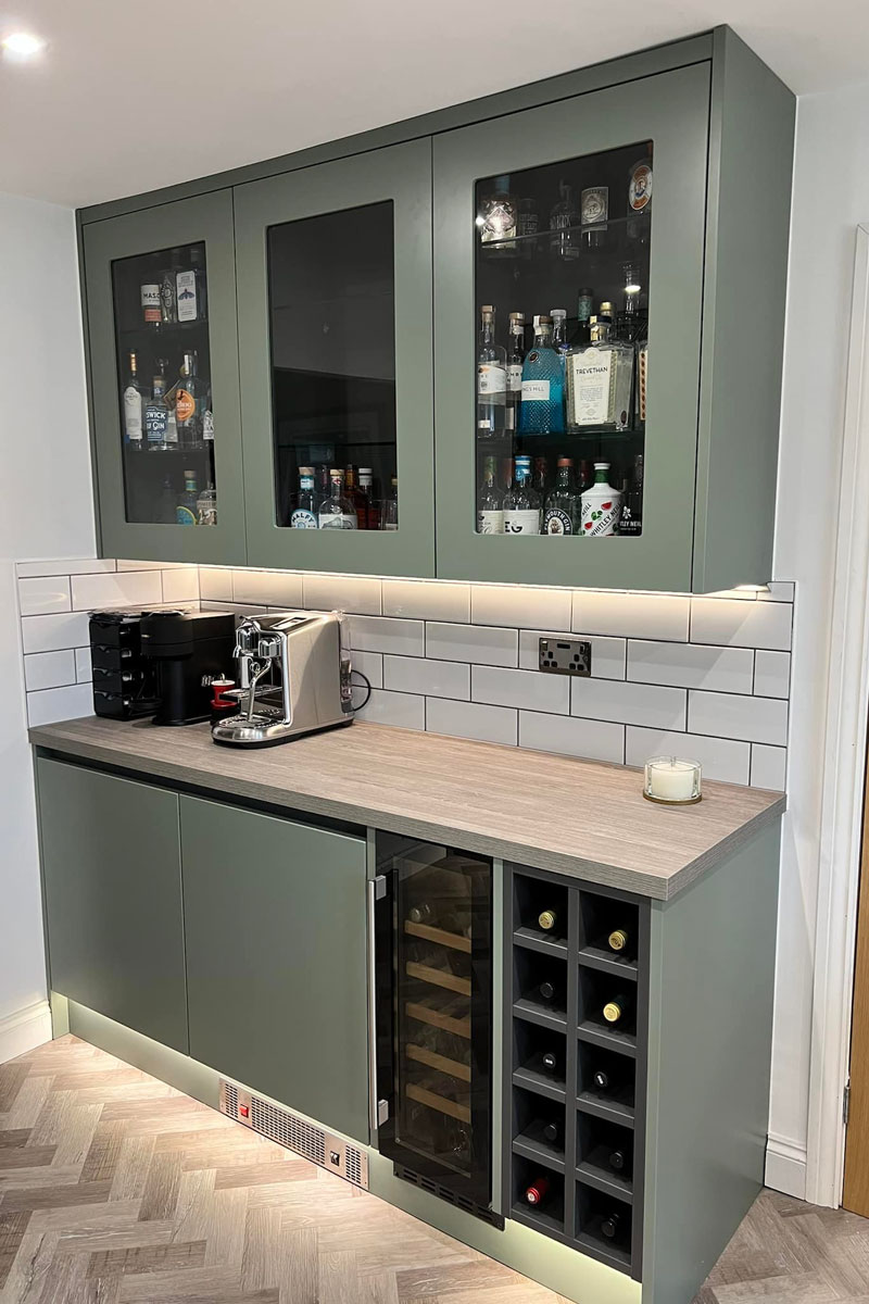 A modern kitchen renovation with wine cooler, green handless cabinets under cabinet lighting in Burnham on Sea
