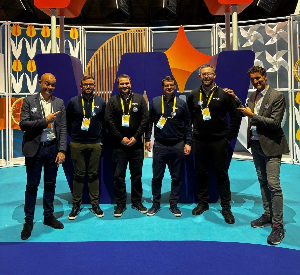 Six members of the IntSys Solutions and HR Path teams at a Workday event, in front of a Workday-branded stand.