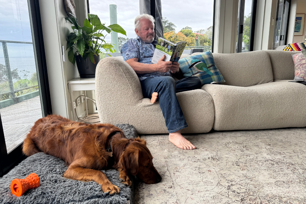 Mark Vette sits and reads while his dog relaxes beside him