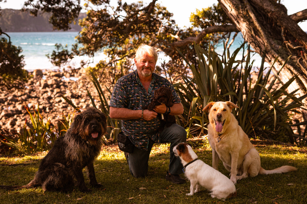 Mark Vette with three dogs sitting on the beach