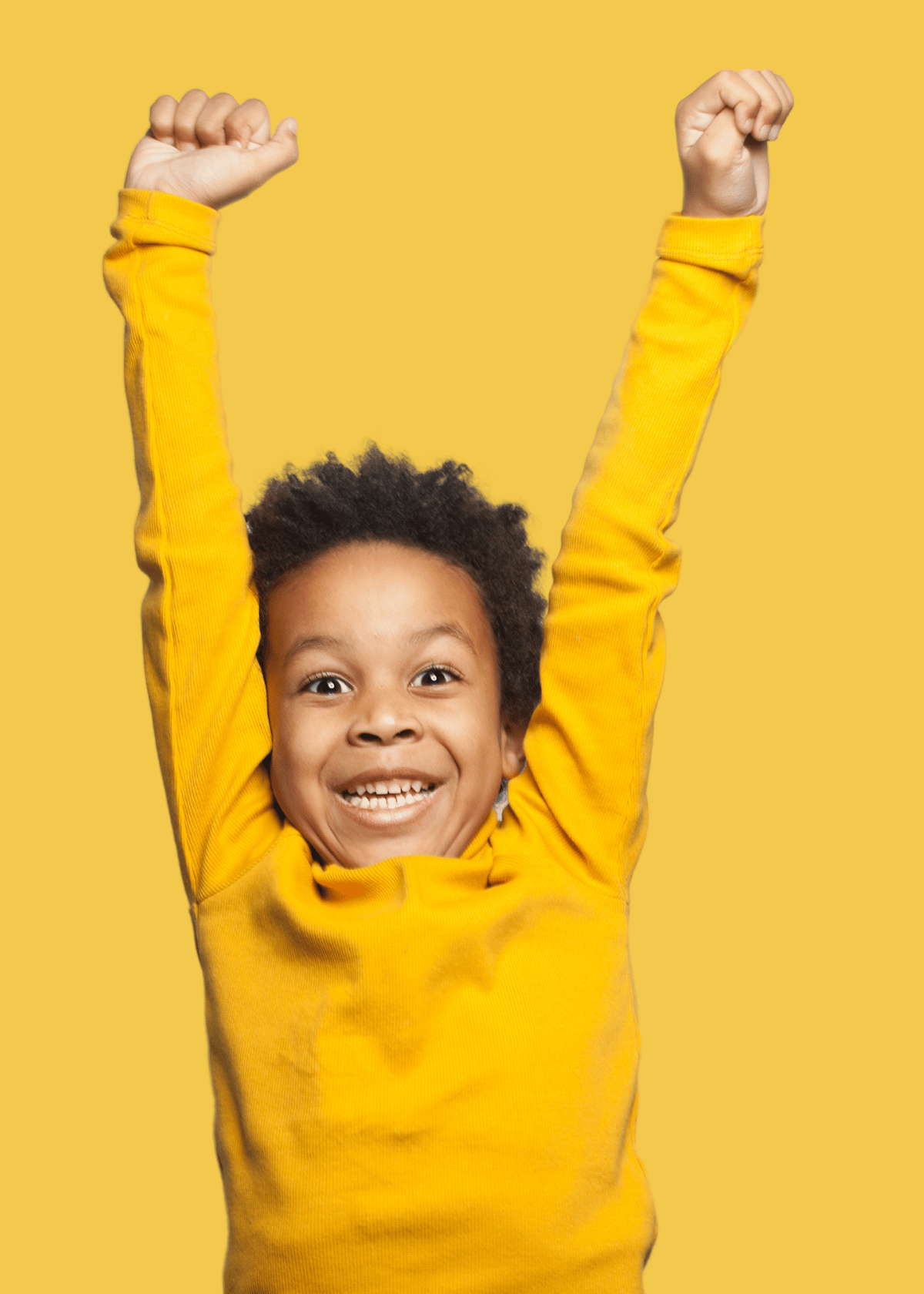 Excited young child with curly hair wearing a bright yellow long-sleeve shirt smiling and raising both arms against a yellow background.