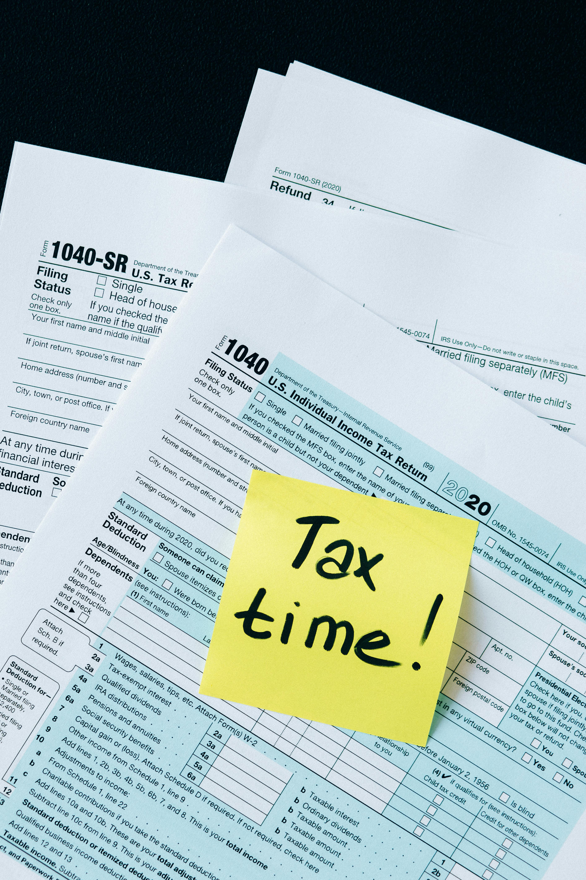 A stack of paper with a post-it note that has 'tax time' written on it