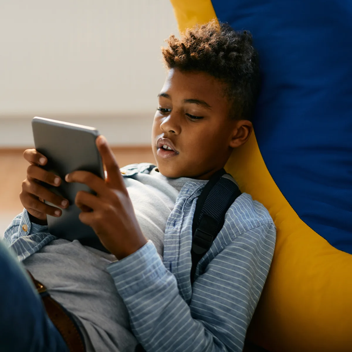 Student reading on a tablet while leaning back on a beanbag